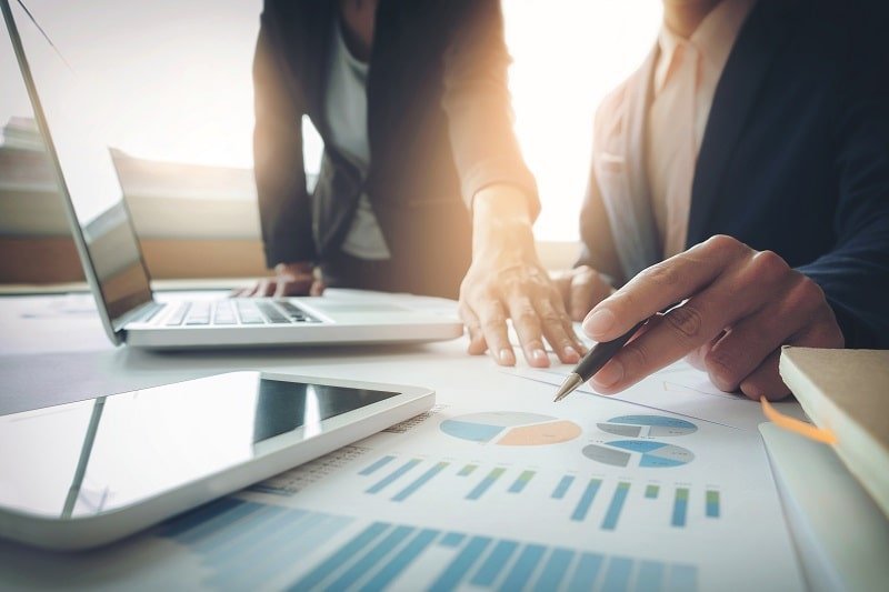 people working at a desk pouring over data